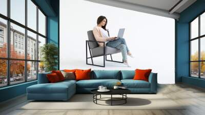 portrait of a young businesswoman sitting in a chair with laptop computer against white background Wall mural